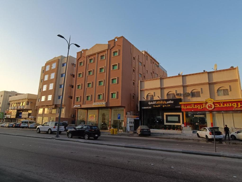 una calle de la ciudad con coches estacionados frente a los edificios en منازل لينة Manazel Lina, en Al Hofuf