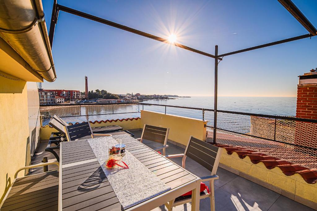 een tafel en stoelen op een balkon met uitzicht op de oceaan bij Apartments Rosana in Umag