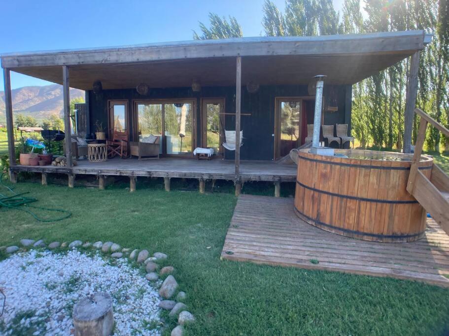 a house with a wooden deck with a hot tub at Hermosa cabaña con hot tub. in Talagante