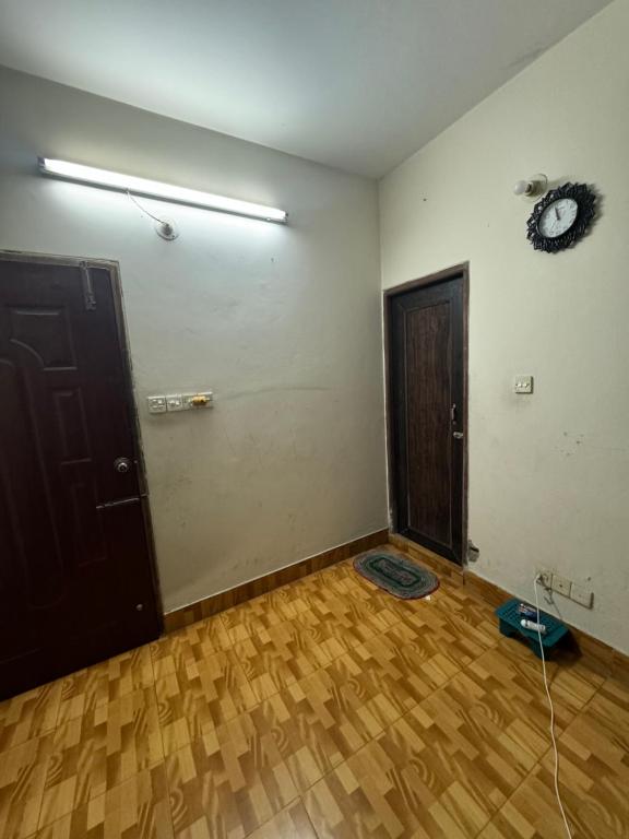 um quarto vazio com duas portas e um piso de madeira em Hassan Imam em Daca
