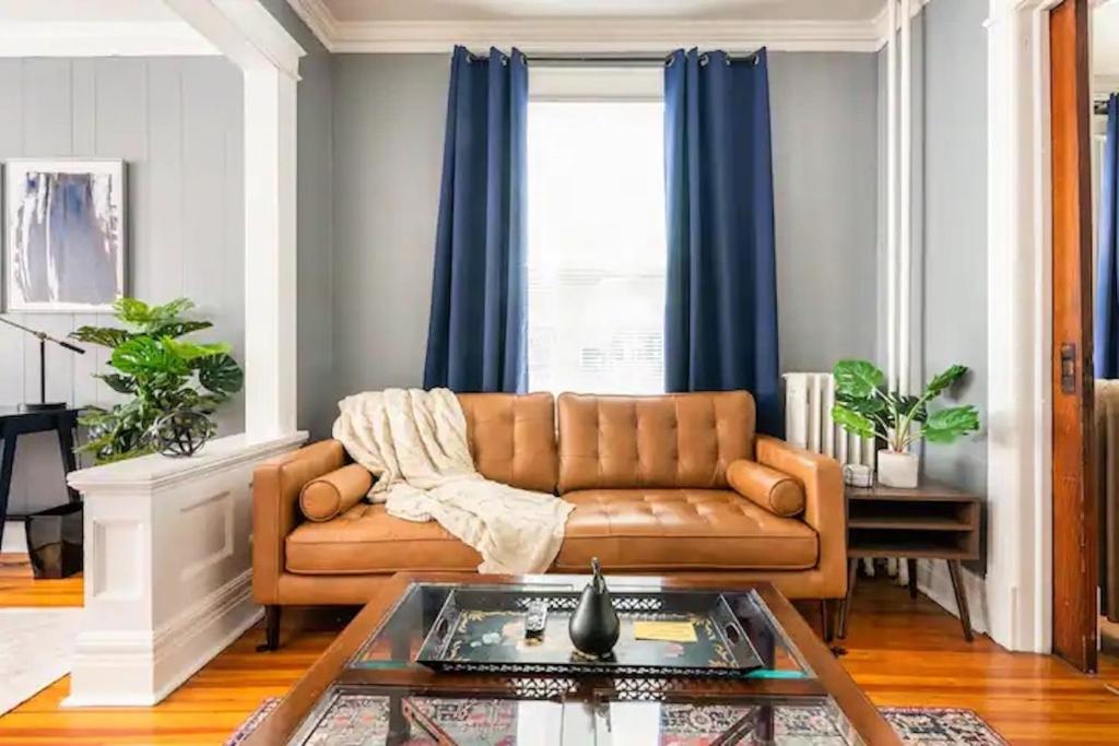 a living room with a brown couch and blue curtains at Perfect for Families and Traveling Professionals in Albany