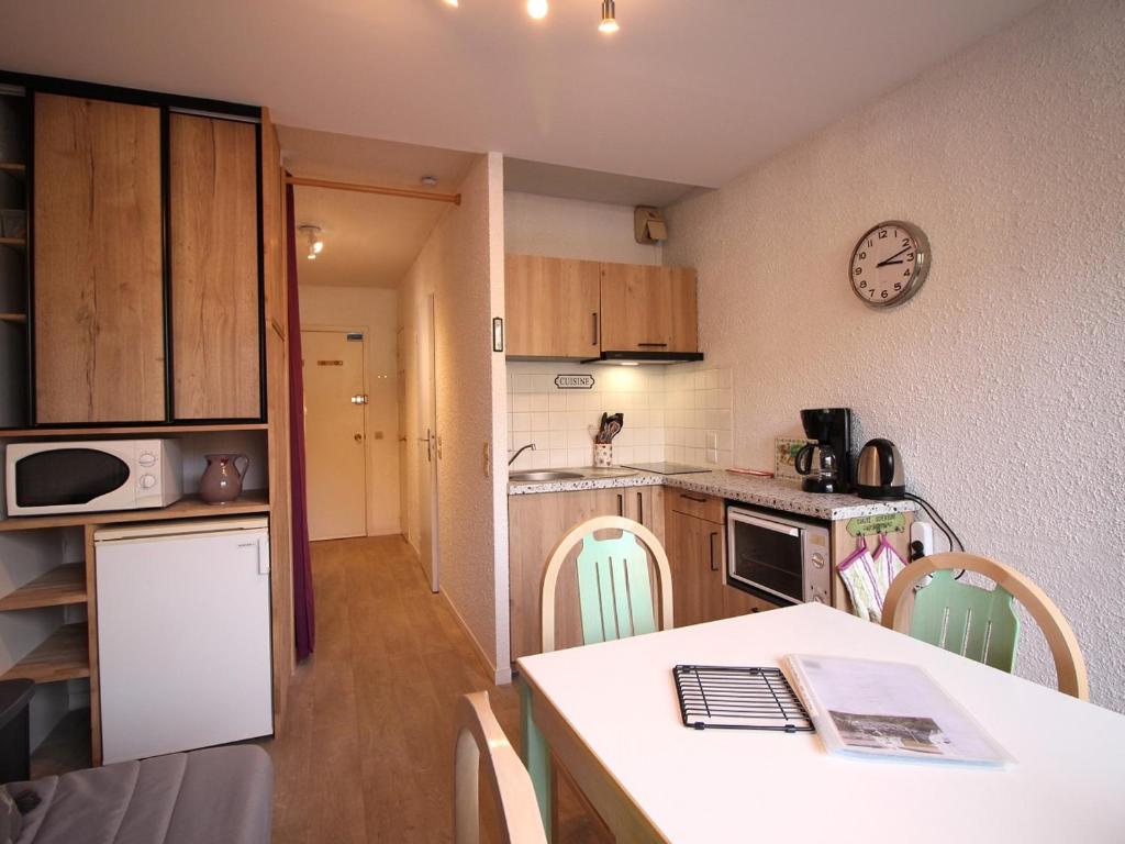 une petite cuisine avec une table et une horloge murale dans l'établissement Studio avec Balcon et Ascenseur - 200m du Centre - FR-1-608-137, à Le Mont-Dore