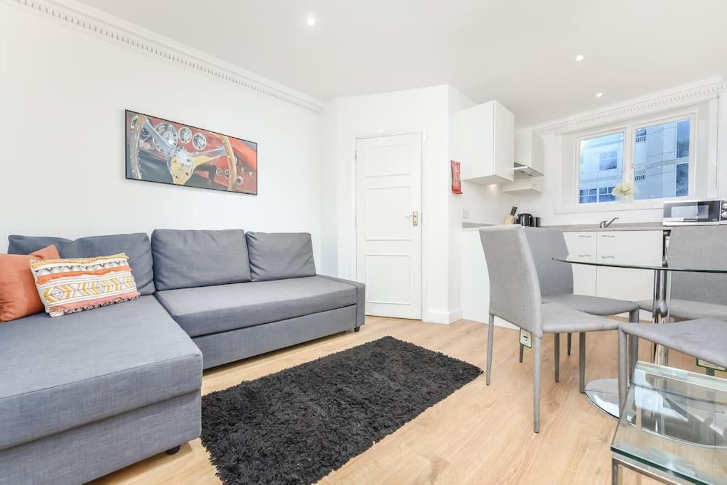 a living room with a couch and a table and a kitchen at 2 Bed Piccadilly Apartment- 4 in London