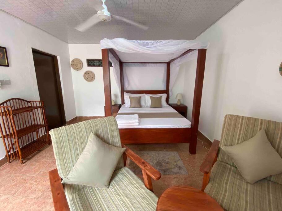 a bedroom with a bed and two chairs at Cynthia’s Homestays@0723632635 in Malindi