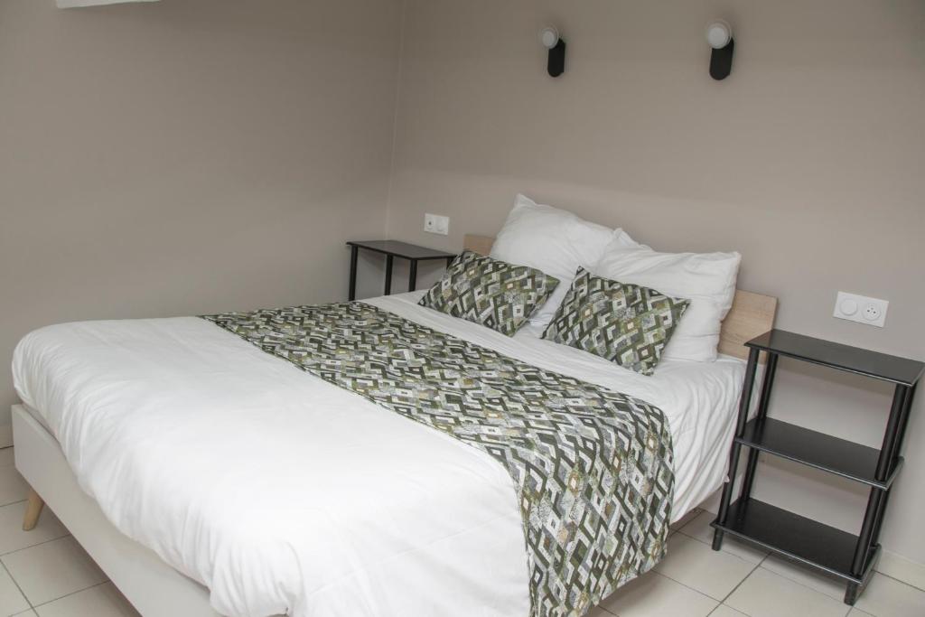 een slaapkamer met een wit bed en twee nachtkastjes bij Le Clos de Manon in Carcassonne