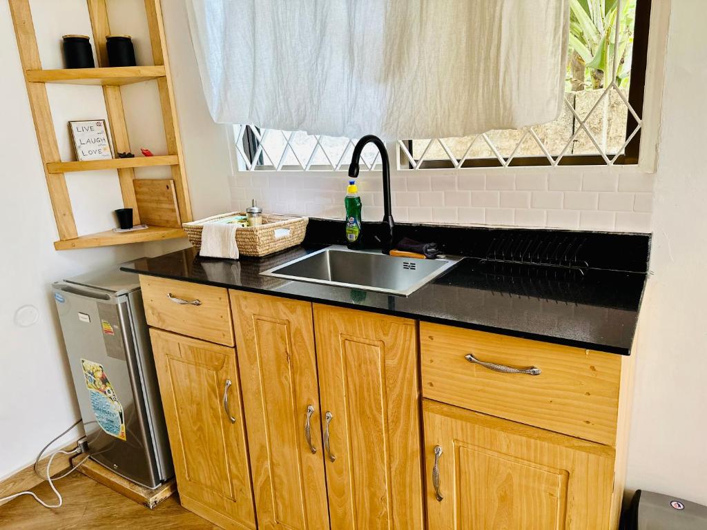 encimera de cocina con fregadero y ventana en Golden hour tiny house en Arusha