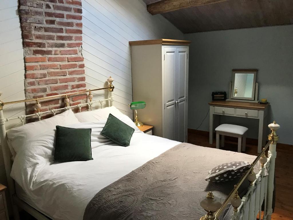 een slaapkamer met een wit bed met groene kussens bij Papillons B&B - beauty, comfort and peace 25 mins from Puy du Fou in Montournais