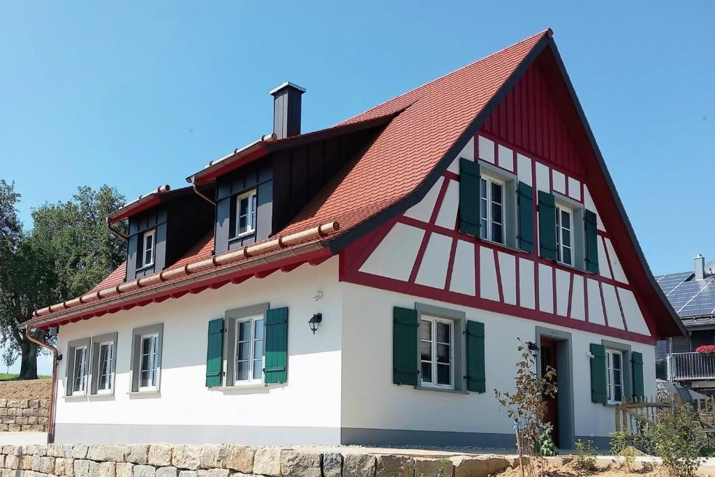 une maison avec un toit rouge et des fenêtres vertes dans l'établissement Landluft Ferien - Wohnung Abendrot, à Heiligenberg