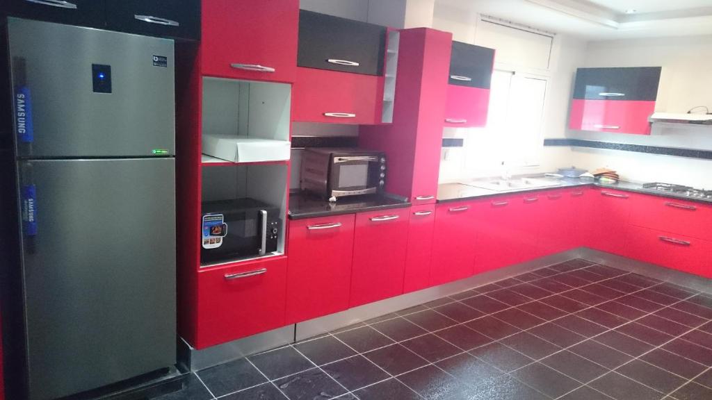 a red kitchen with red cabinets and a microwave at MAISON SIDI BOU SAID in Hammamet