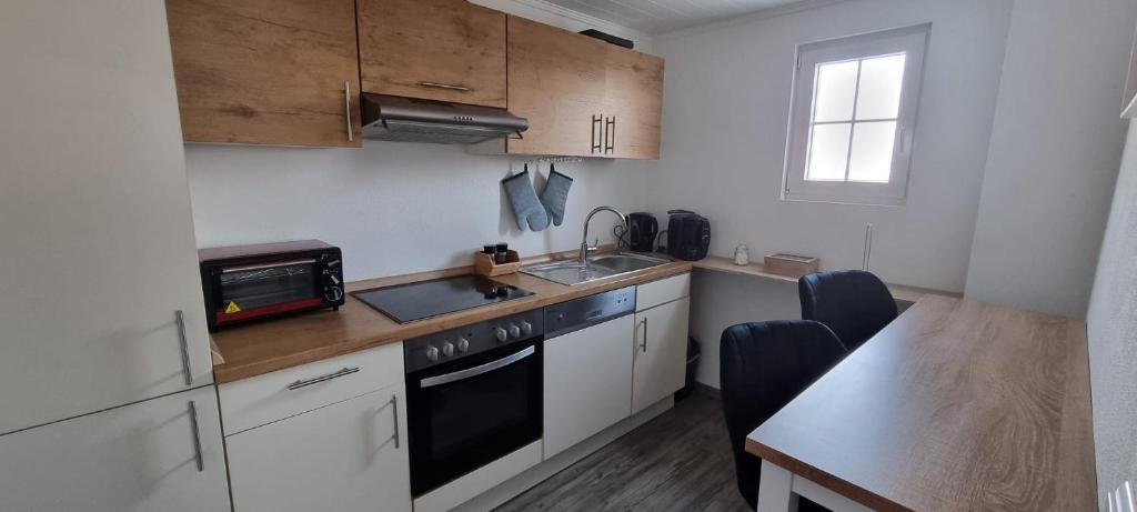 a kitchen with white cabinets and a sink and a table at Ferienwohnung Sigmarino in Sigmaringen