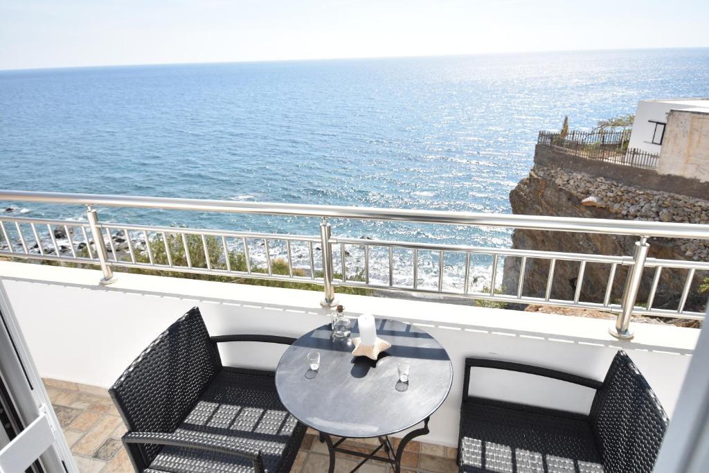 balcón con mesa, sillas y vistas al océano en House with view sound of waves en Paránimfoi