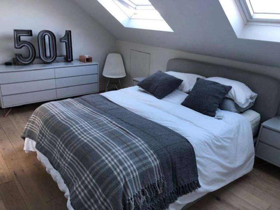 a bedroom with a large bed and a skylight at Stunning Modern Large 5 Bed House Willesden in London