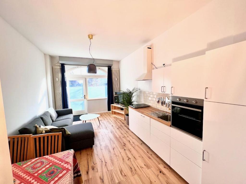 a kitchen with white cabinets and a living room at Central apartment in trendy Friedrichshain in Berlin