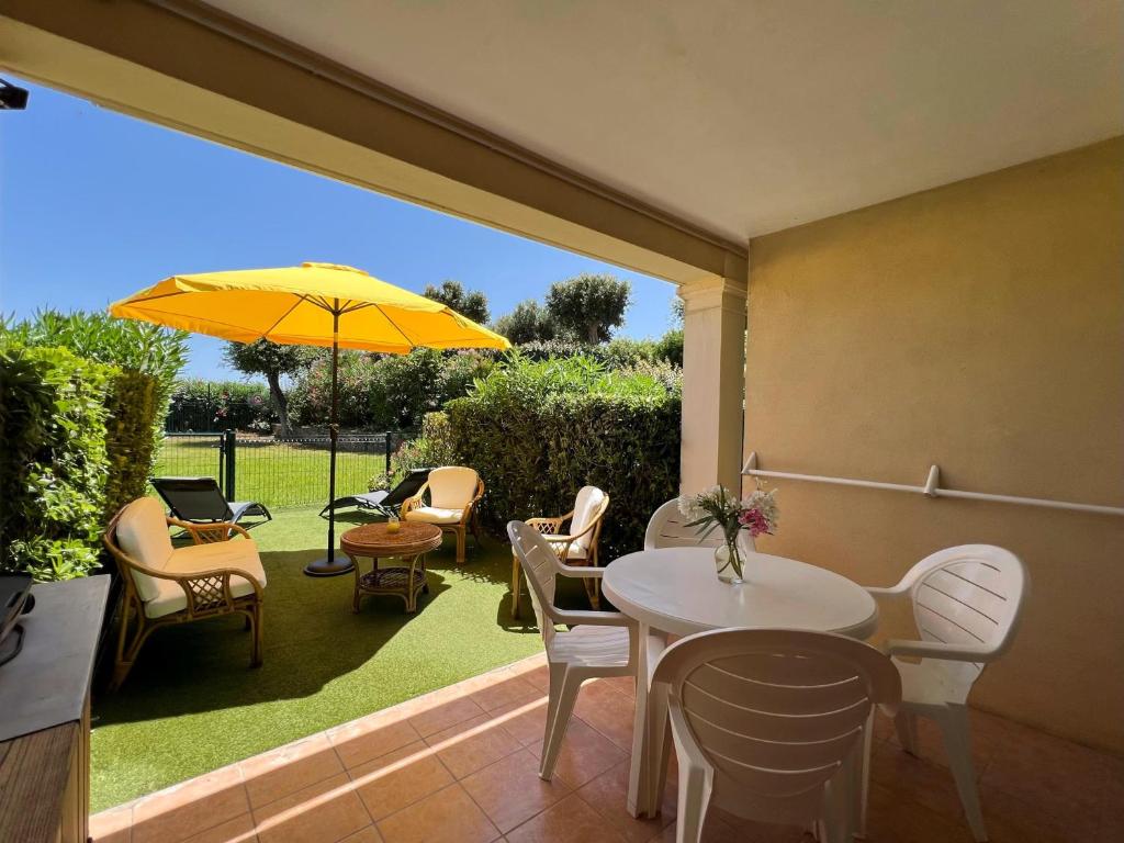 eine Terrasse mit einem Tisch, Stühlen und einem Sonnenschirm in der Unterkunft Appartement au Hameau des Issambres Le Pamakior in Les Issambres