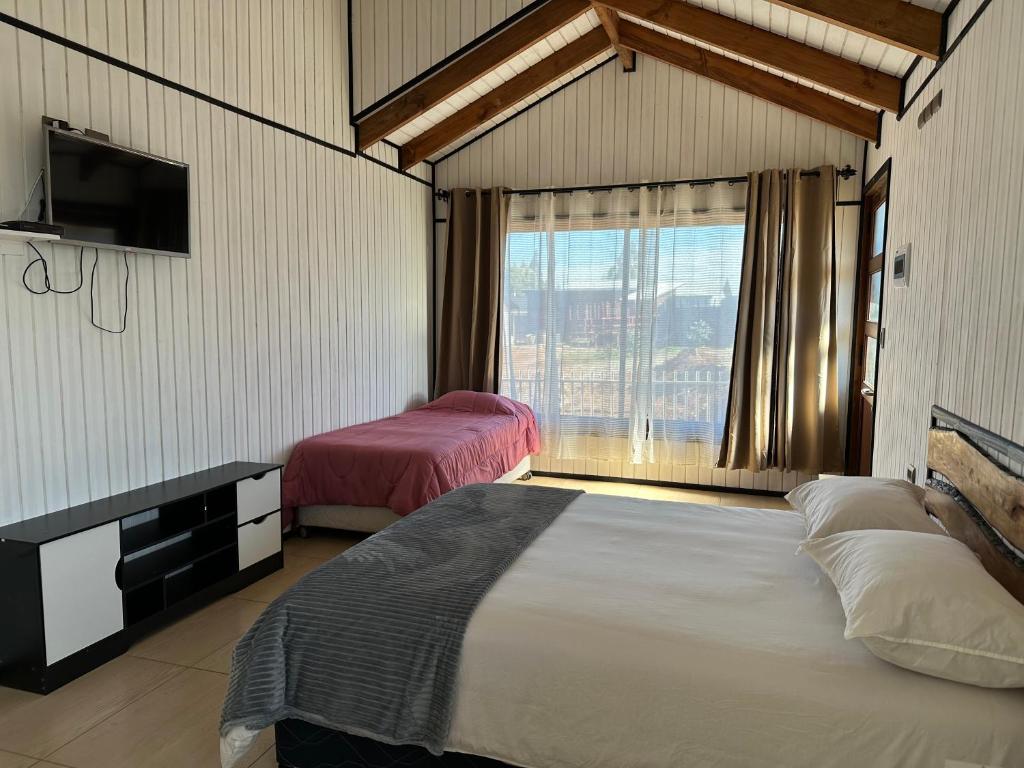 1 dormitorio con 2 camas y ventana grande en Complejo Turístico Los Laureles Arauco, en Arauco