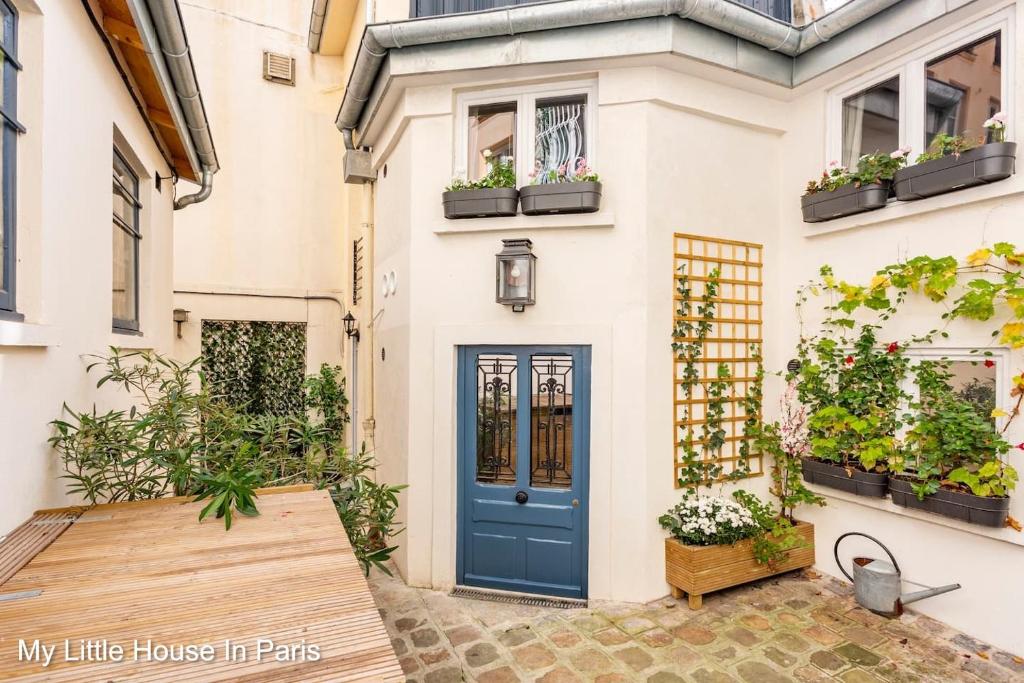 a blue door on a white house with potted plants at My Little House in Paris * Hypercentre * Climatisé in Paris