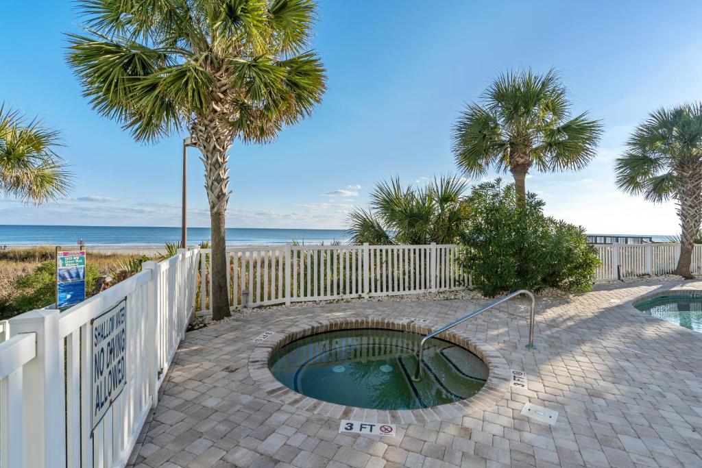 a small swimming pool next to a fence and the beach at Oceanfront Get Away in Myrtle Beach