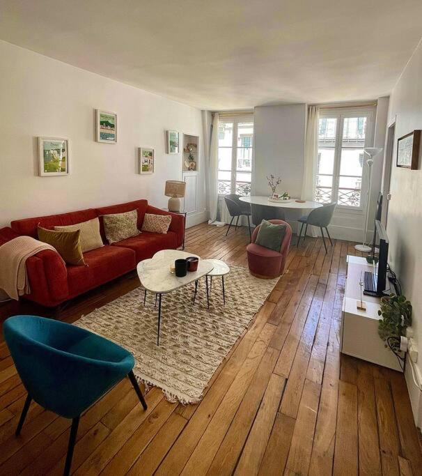 ein Wohnzimmer mit einem roten Sofa und einem Tisch in der Unterkunft Appartement proche Arc Triomphe / Champs Elysées in Paris