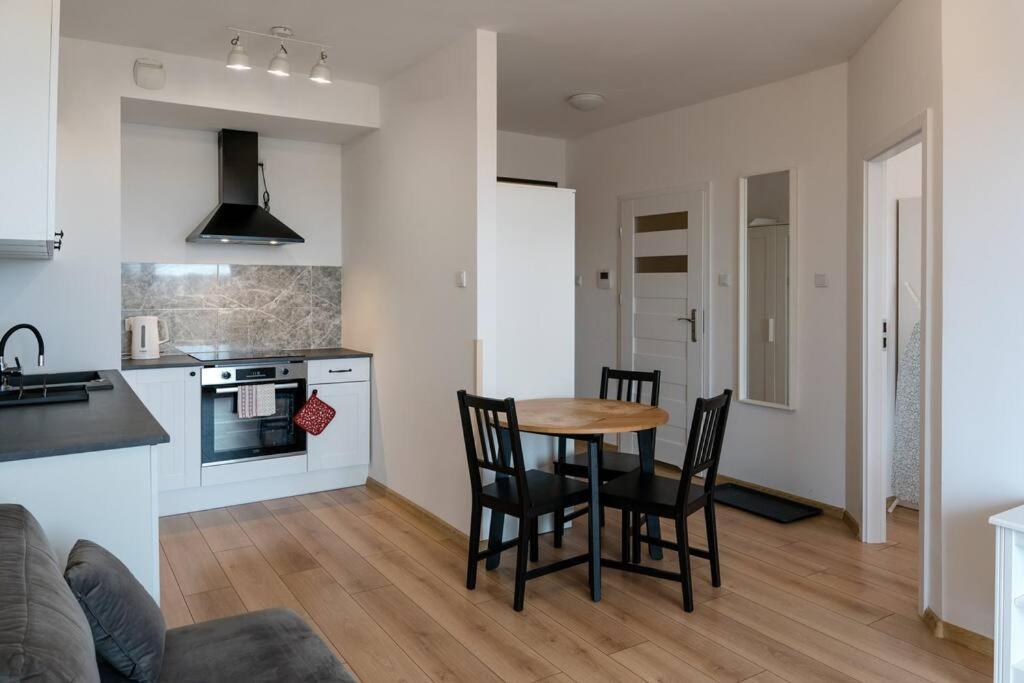 a kitchen and living room with a table and chairs at Apartament Zajezdnia Wrzeszcz Gdańsk 1 in Gdańsk
