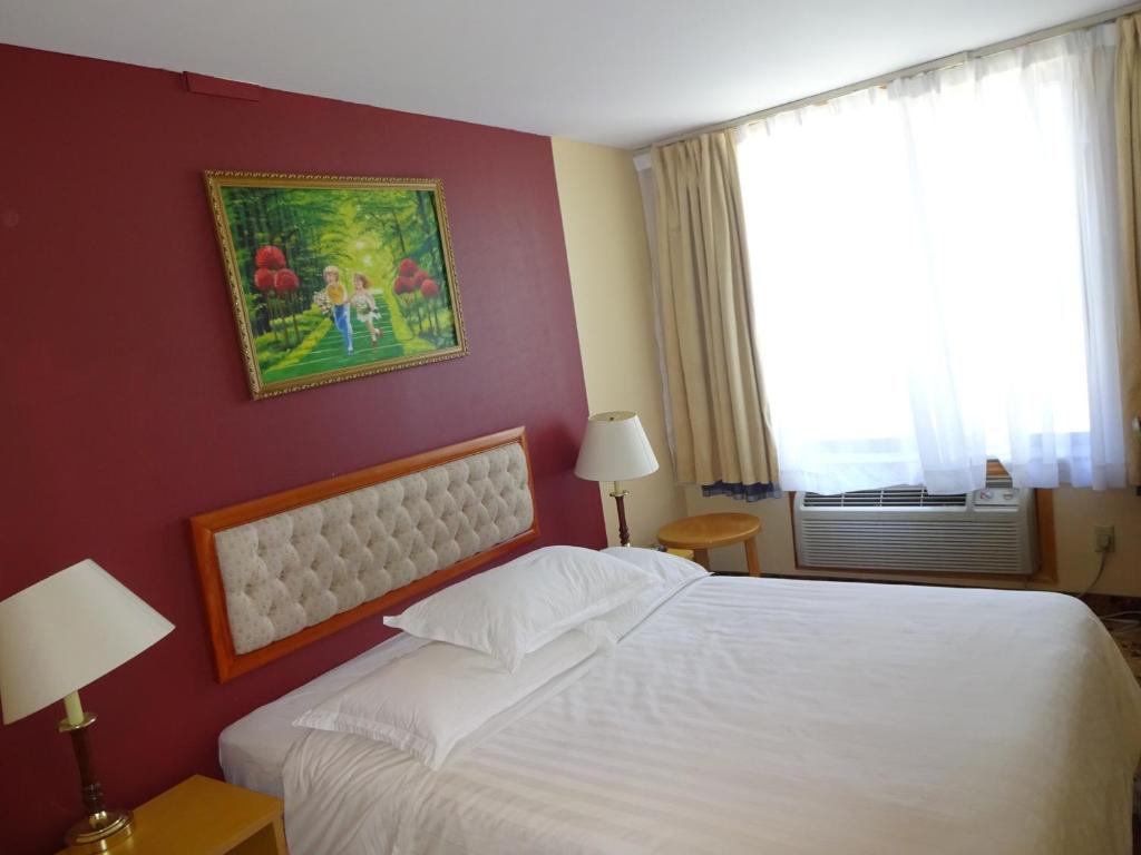 a bedroom with a white bed and a painting on the wall at Flushing Hotel in Queens