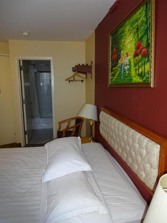 a bed in a bedroom with a painting on the wall at Flushing Hotel in Queens