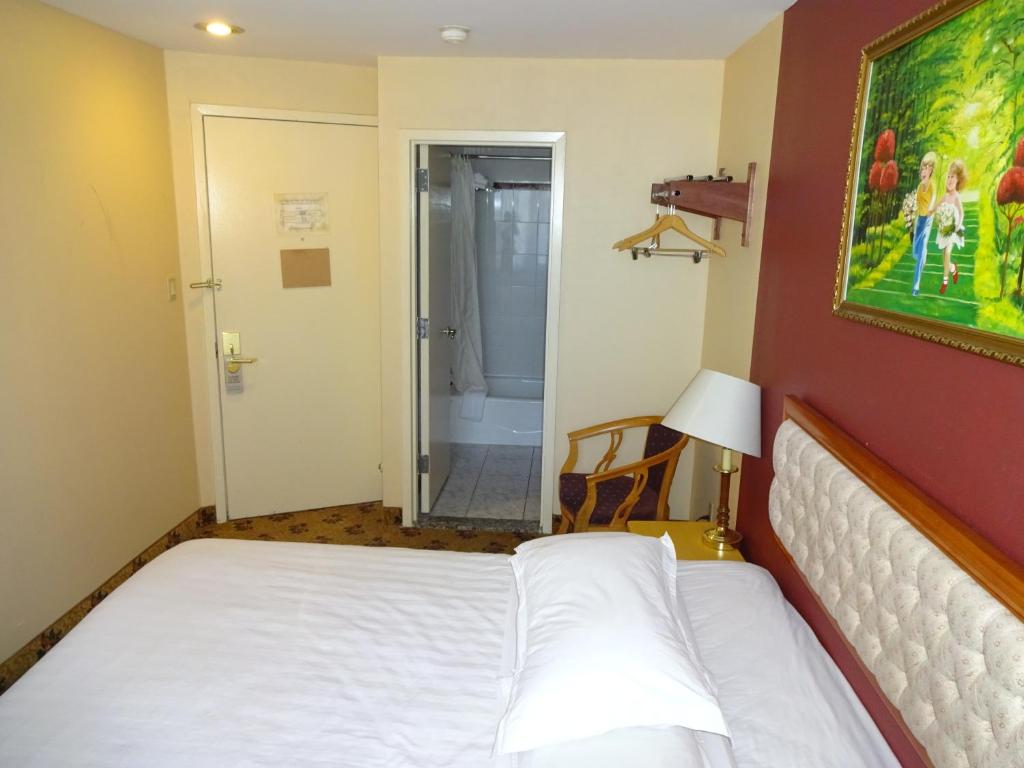 a bedroom with a bed and a painting on the wall at Flushing Hotel in Queens
