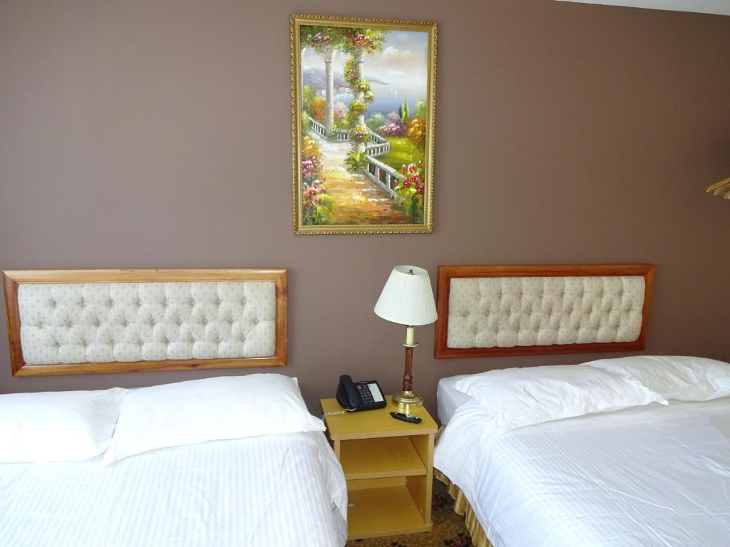 two beds in a hotel room with a picture on the wall at Flushing Hotel in Queens