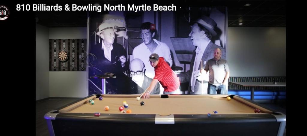a man playing a game of pool in a room at Oceanfront Get Away in Myrtle Beach