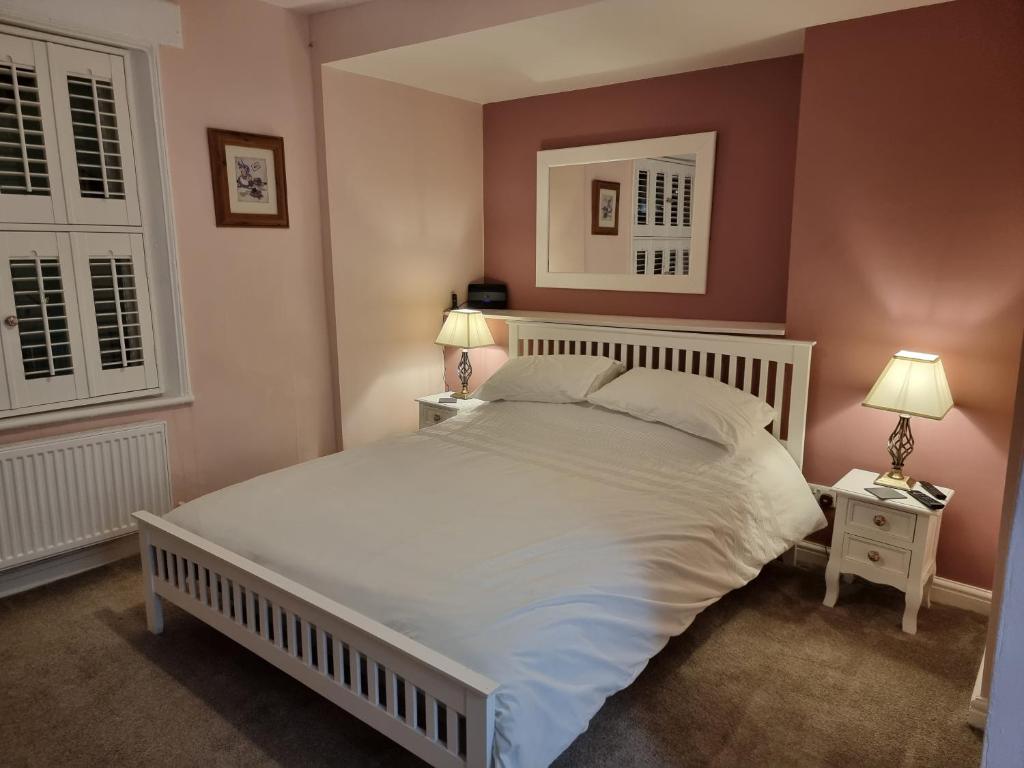 a bedroom with a large white bed with two lamps at Poppy Cottage in Whitby