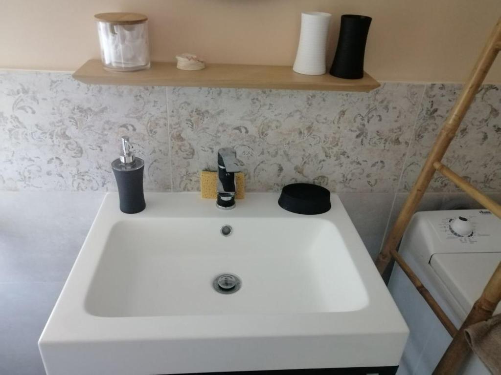 a bathroom with a white sink and a washer at L'Embellie un gîte tout confort et cocooning in Villefranche-sur-Saône