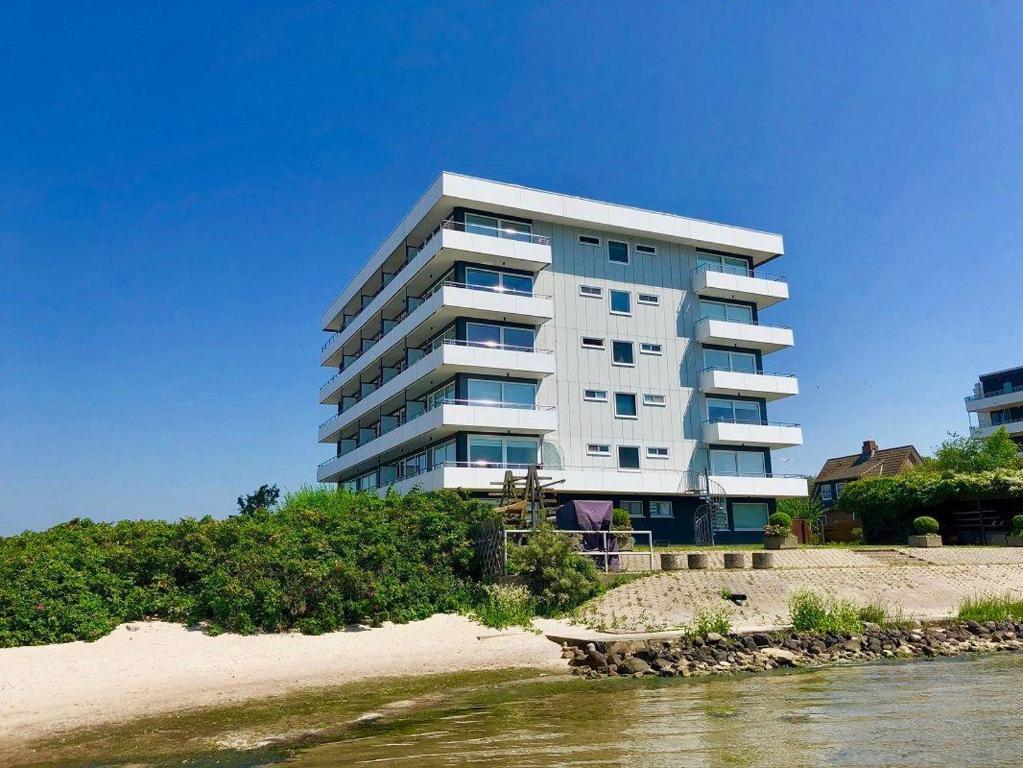 een hoog gebouw op het strand naast een waterlichaam bij Haus-Steinwarder-7-Wohnung-Strandbude-17 in Heiligenhafen