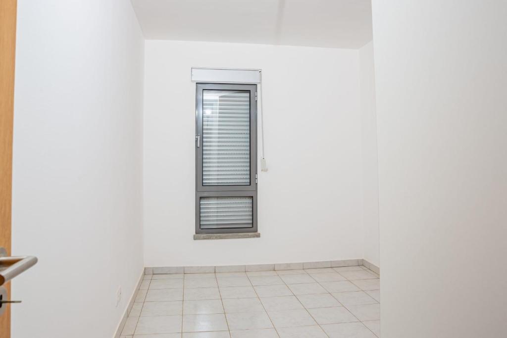 a white room with a window and a tiled floor at Conxixa in Praia