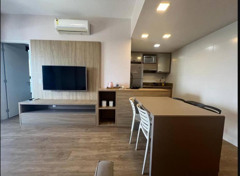 a kitchen and living room with a table and a television at Aparthotel Astron in Salvador