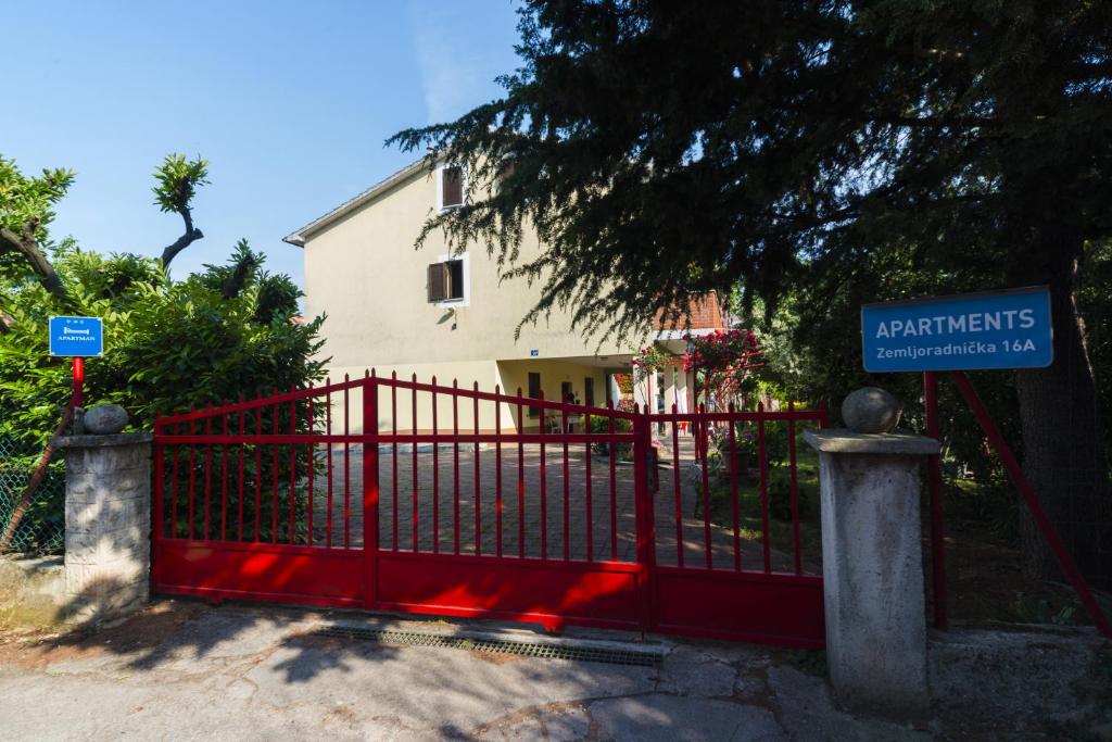 a red gate with a sign in front of a house at Apartments Milica in Umag