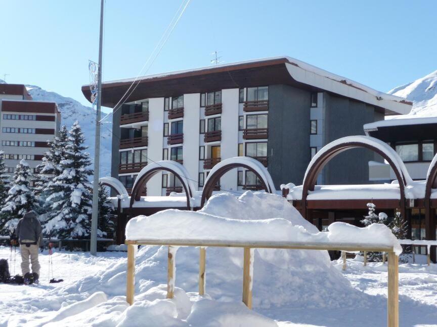 un banco cubierto de nieve frente a un edificio en Résidence Chanteneige - Freeloc Immobilier, en Les Menuires