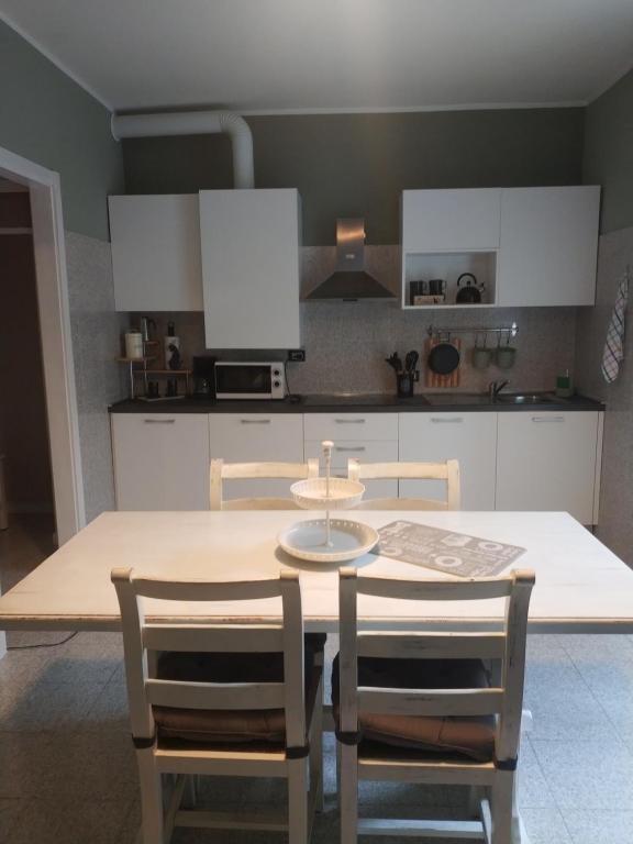 eine Küche mit einem Tisch und Stühlen sowie weißen Schränken in der Unterkunft Casa Coralba in Pavia