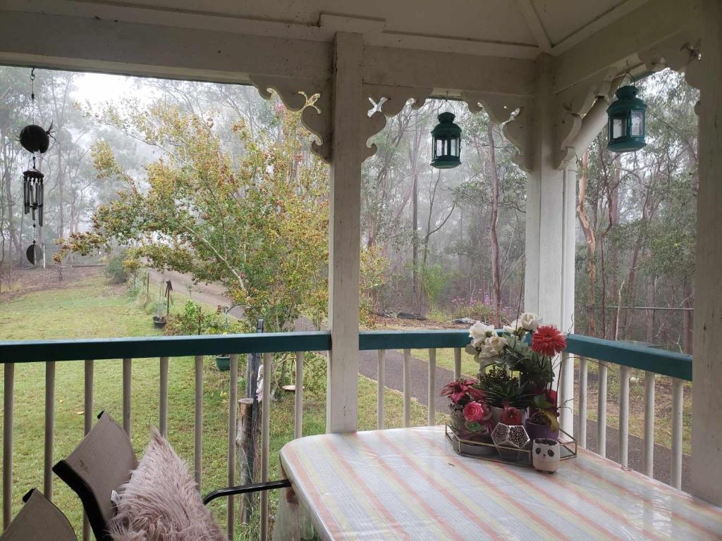 un porche con una mesa y un jarrón de flores en Rustic Sunflower, en Mount Crosby
