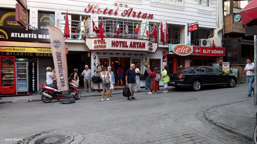 un grupo de personas de pie en una calle frente a las tiendas en Artan Hotel, en Isparta