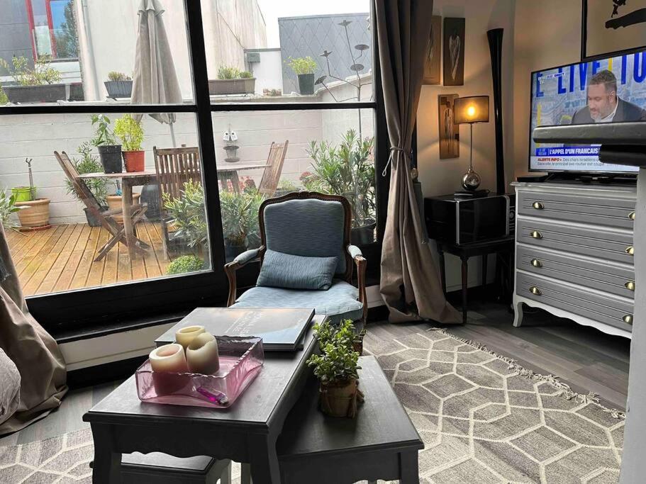uma sala de estar com uma televisão, uma cadeira e uma mesa em Joli studio avec terrasse em Roubaix