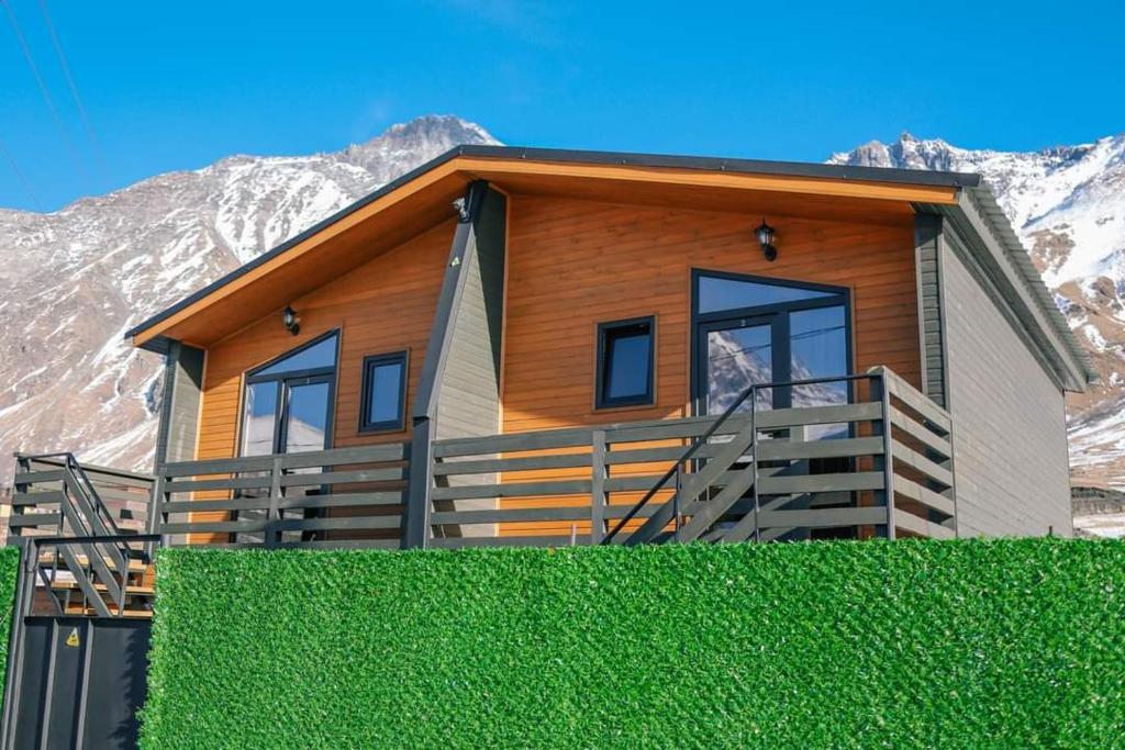 una casa con una siepe verde davanti di SAME Cottage Kazbegi a Kazbegi