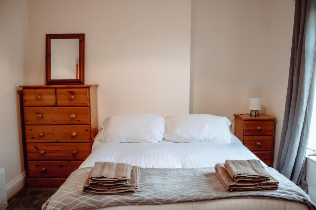 een slaapkamer met een bed, een dressoir en een spiegel bij Rustic Cottage in Heart of Town in Otley