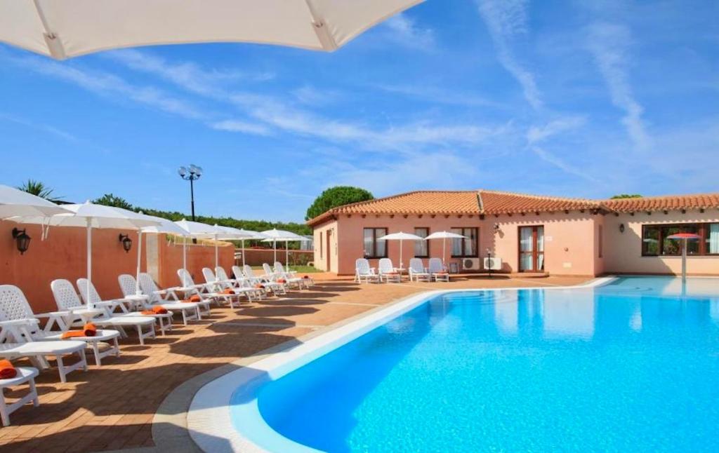 una piscina con sillas y sombrillas frente a una casa en ISA-Residence with swimming-pool in Vignola Mare, apartments with air conditioning and private outdoor area, en Vignola Mare