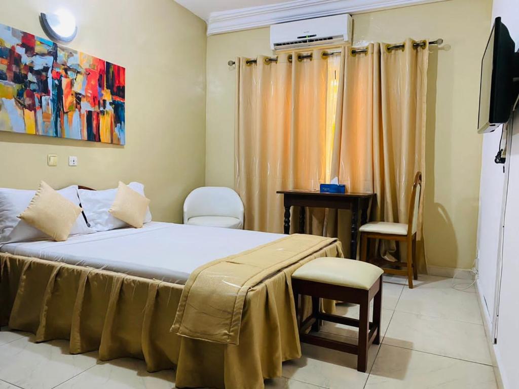 1 dormitorio con 1 cama, mesa y sillas en Acropole Hotel, en Cotonou