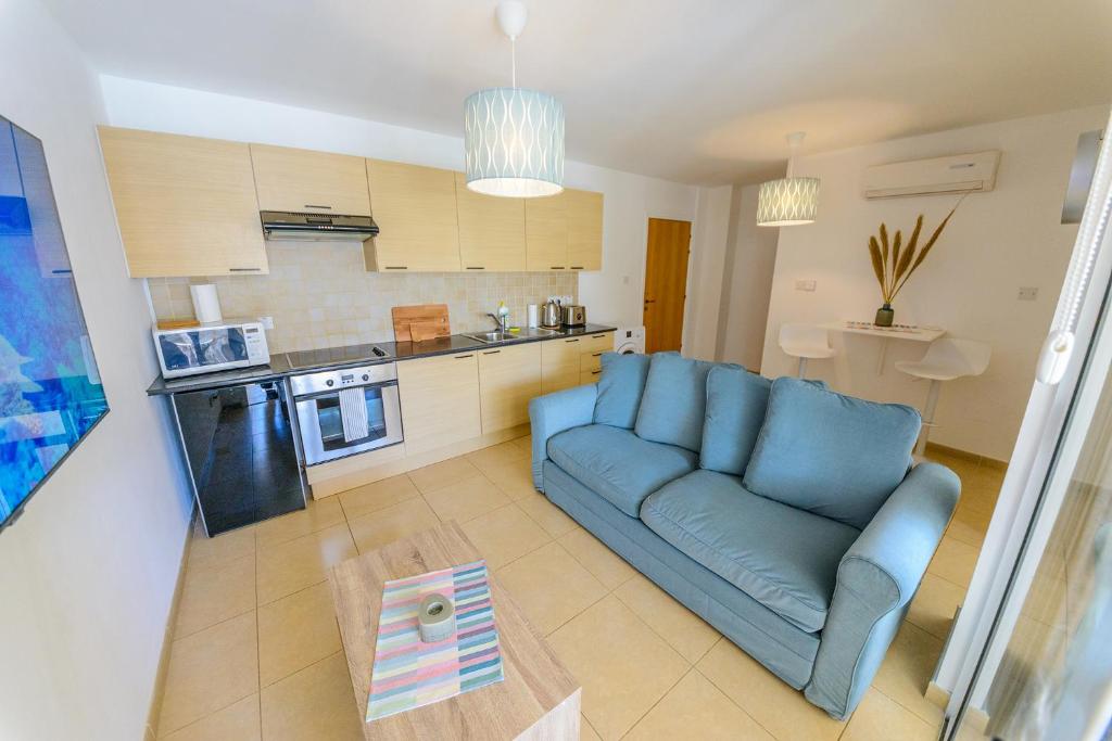 a living room with a blue couch and a kitchen at 1 bed, Kapparis, Thea - 1B in Paralimni