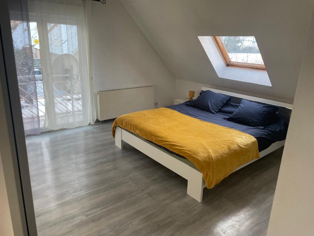 a bedroom with a bed with a yellow blanket and a window at Au petit Logelbach in Wintzenheim