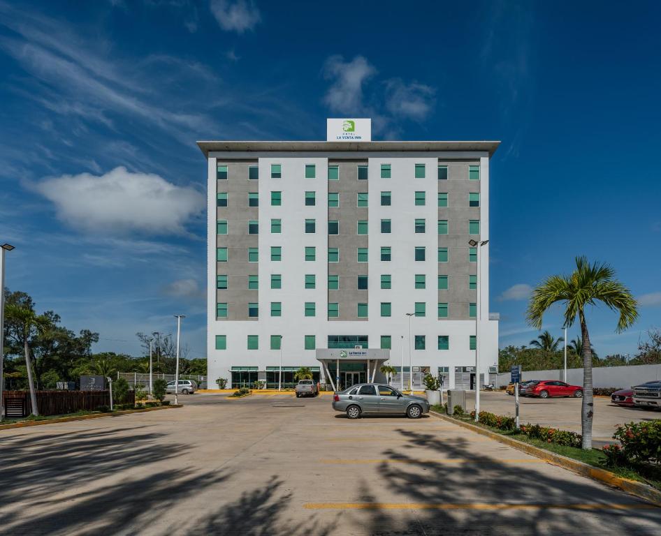 un grand bâtiment blanc avec une voiture garée dans un parking dans l'établissement La Venta Inn Ciudad del Carmen, à Ciudad del Carmen