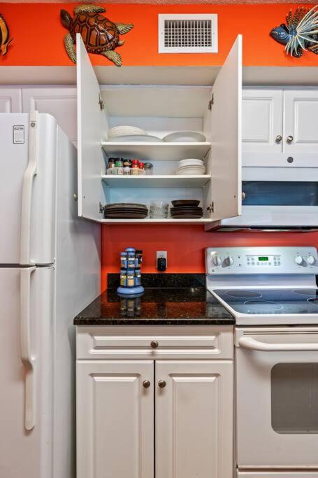 a kitchen with white cabinets and an orange wall at Oceanfront Get Away in Myrtle Beach