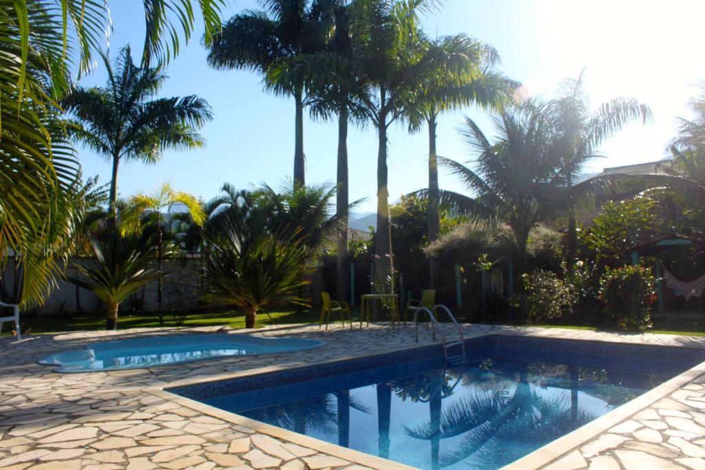 a swimming pool with palm trees in the background at Pousada Brasil Paraty in Paraty