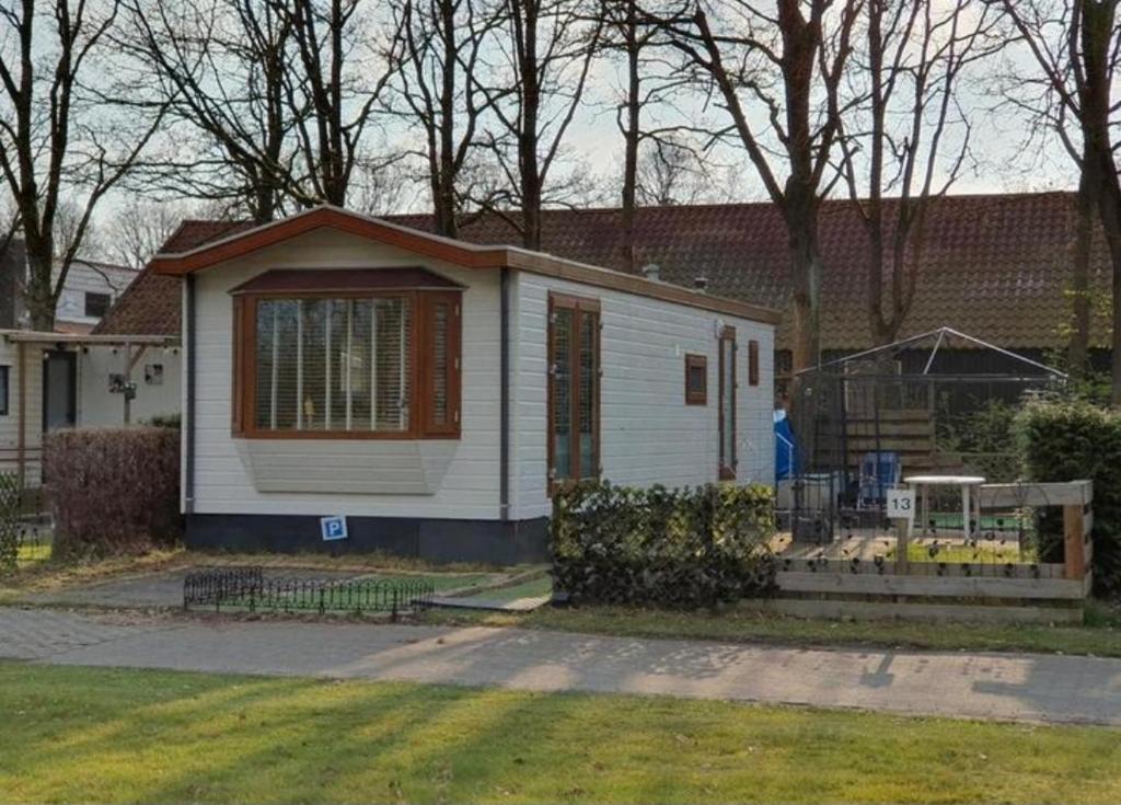 una pequeña casa blanca con una valla en un patio en Het kleine huis en Schoonloo