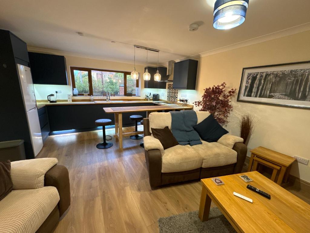 uma sala de estar com um sofá, uma mesa e uma cozinha em New city flat, 3 x double bed en-suite bedrooms, private kitchen & lounge, free private parking & own workspaces em Exeter